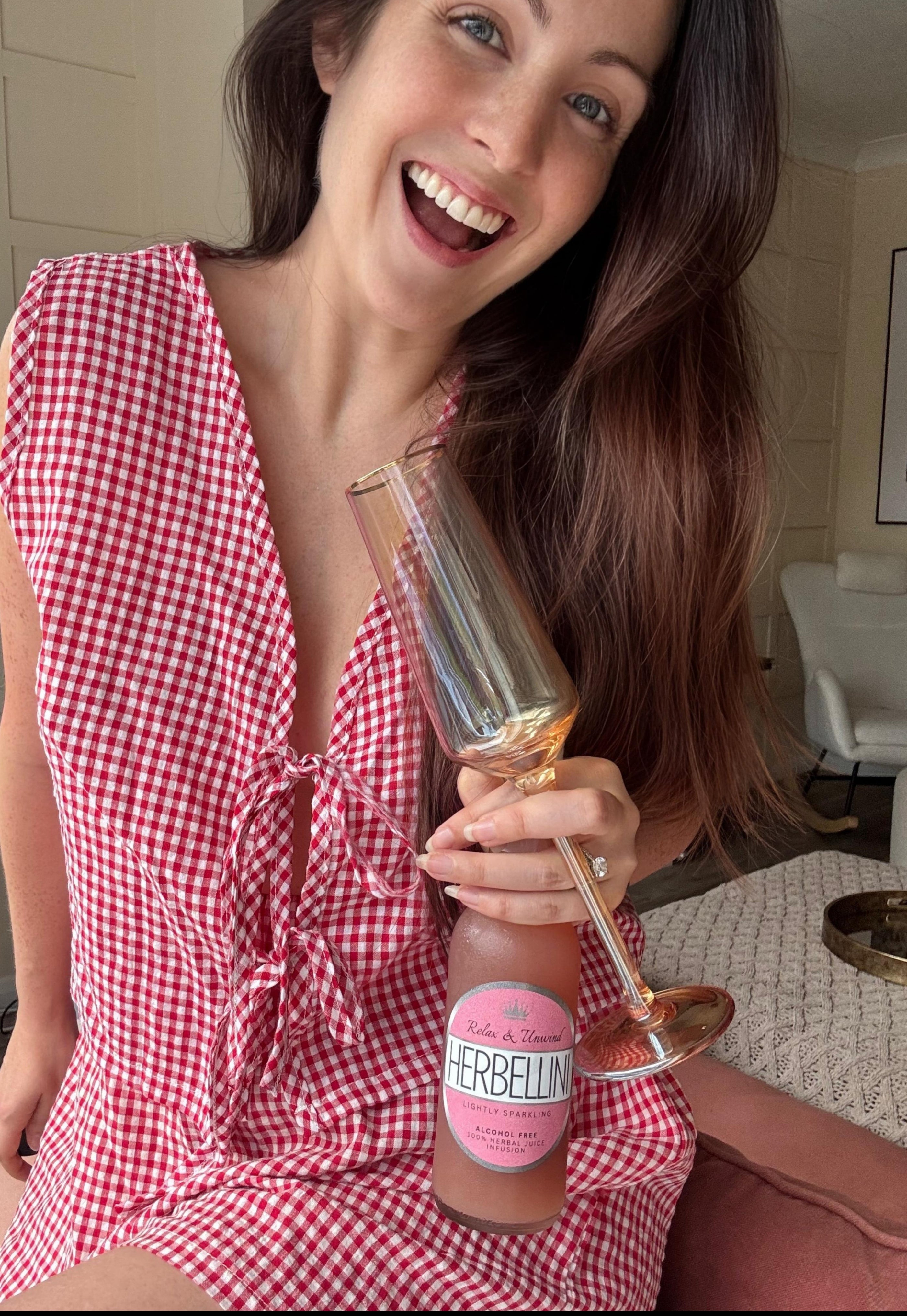 Lady holding a bottle and glass of Herbellini 
